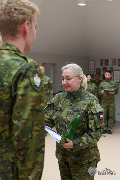 pułkownik obrzut wręcza funkcjonariuszom akty mianownia, które umieszczone są w zielonej teczce papierowej