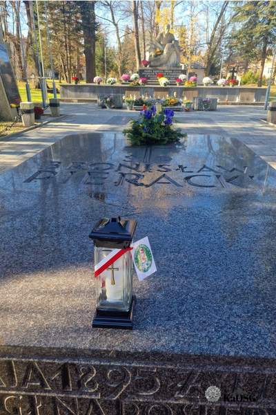 Grób Pierackiego a na nim zapalony znicz z biało - czerwoną tasiemką i logiem Karpackiego Oddziału Straży Granicznej