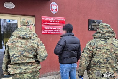 zatrzymany cudzoziemiec jest wprowadzany przez dwóch funkcjonariuszy sg do siedziby placówki sg w kielcach.