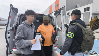 dwaj zatrzymani cudzoziemcy wysiadają z pojazdu sg  typu więźniarka. w rękach trzymają dokumenty. są w asyście nieumundurowanego funkcjonariusza straży granicznej
