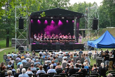 Publiczność siedzi przed sceną, na której występuje Orkiestra Reprezentacyjna Straży Granicznej