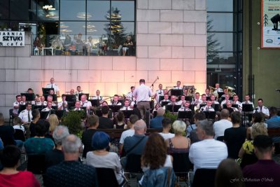 Publiczność siedzi przed sceną, na której występuje Orkiestra Reprezentacyjna Straży Granicznej