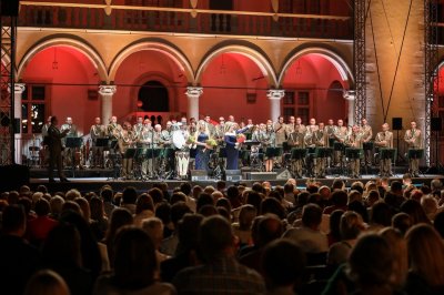 Zakończenie koncertu, muzycy orkiestry stoją. Wokalistki i dyrygent stoją na scenie.