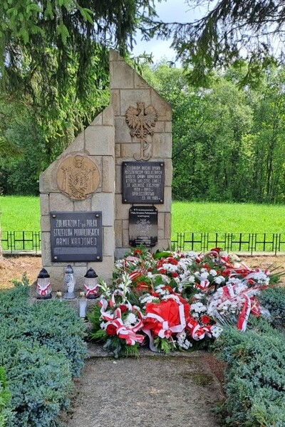 Pomnik upamiętniający żołnierzy 1 Pułku Strzelców Podhalańskich Armii Krajowej, przed nim złożone wiązanki kwiatów i znicze.