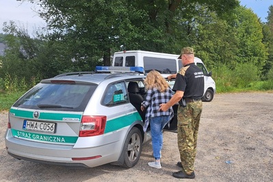 Zatrzymana przez patrol Straży Granicznej obywatelka Mołdawii wsiada w asyście jednego z funkcjonariuszy do radiowozu z napisem Straż Graniczna. W tle bus, którym podróżowała kobieta.