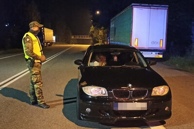 7 Turków zatrzymano w Chyżnem zatrzymany pojazd z nielegalnymi imigrantami obok niego stoi funkcjonariusz Straży Granicznej.