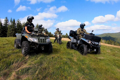 Funkcjonariusze KaOSG współdziałają i pomagają Funkcjonariusze Straży Granicznej obserwujący teren Gorczańskiego Parku Narodowego. Funkcjonariusze siedzą na pojazdach służbowych typu quad.