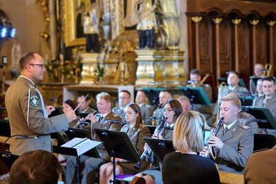 Wnętrze krotoszyńskiej bazyliki. Około 10 funkcjonariuszy gra na instrumentach, po prawej stronie stoi funkcjonariusz dyrygujący Orkiestrą.