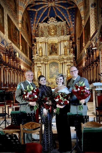 Wnętrze katedry św. Mikołaja Biskupa w Kaliszu. W tle ołtarz, na pierwszym planie soliści oraz naczelnik Orkiestry Reprezentacyjnej SG z bukietami kwiatów.