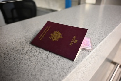 Na ladzie przy stanowisku kontroli granicznej leży francuski paszport w kolorze bordowym. W środku włożone jest francuskie prawo jazdy, którego róg wystaje z paszportu.