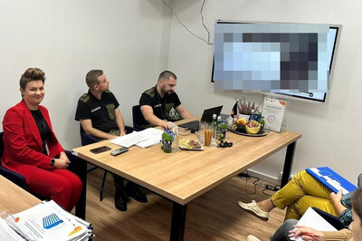 Szkolili pracowników MUW w Krakowie funkcjonariusze straży granicznej omawiający prezentacje która wyświetlana jest na dużym ekranie zamieszczonym na ścianie. obecni są również pracownicy urzędu.