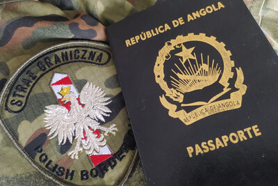 Na położonym mundurze, którego widać tylko skrawek, leży położony emblemat Straży Granicznej oraz paszport wydany przez wadze Angoli.