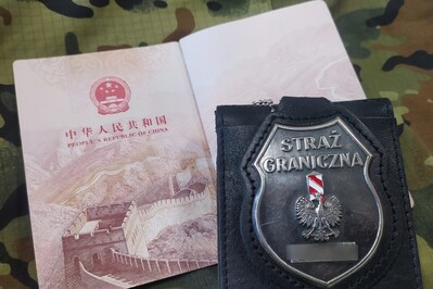 Otwarte wewnętrzne - 2 strony - paszportu chińskiego. Na nim położona odznaka funkcjonariusza Straży Granicznej.