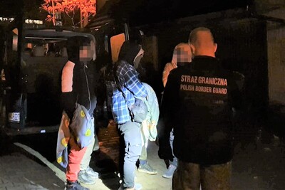 Bezskutecznie próbował przewieźć 5 Syryjczyków pora nocna. zatrzymani cudzoziemcy stojący przed budynkiem placówki straży granicznej w Zakopanem. obok nich funkcjonariusz straży granicznej oraz pojazd służbowy