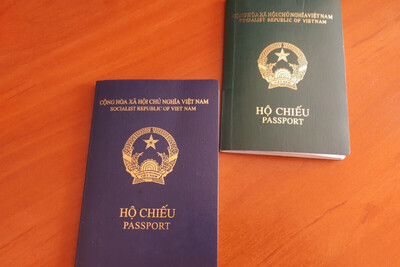 Na biurku leżą dwa paszporty wietnamskie. Jeden w kolorze zielonym a drugi w kolorze granatowym.