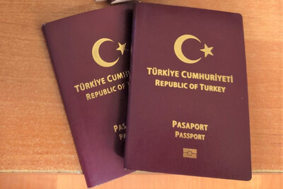 Na biurku leżą dwa paszporty tureckie. Okładki w kolorze bordowym ze złotym napisem, półksiężycem i gwiazdą.