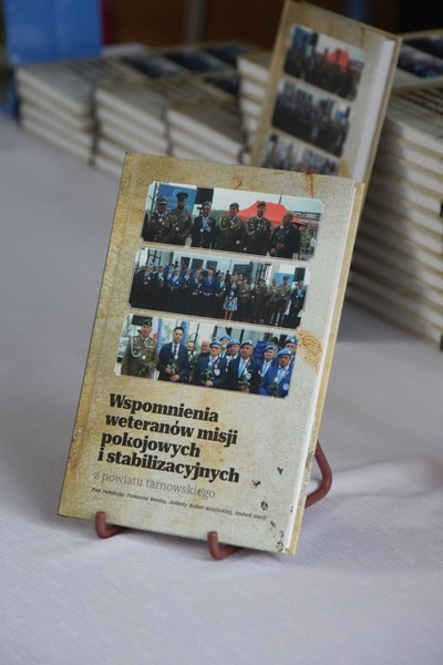 Na stole leży wyeksponowany egzemplarz książki pt. &quot;Wspomnienia weteranów misji pokojowych i stabilizacyjnych z powiatu tarnowskiego&quot;.
