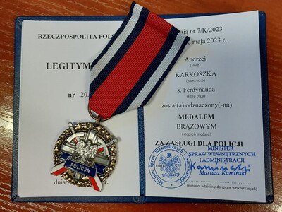 Na biurku leży legitymacja, a na niej przyznany Brązowy Medal za Zasługi dla Policji, który otrzymał ppłk. SG Andrzej Karkoszka.