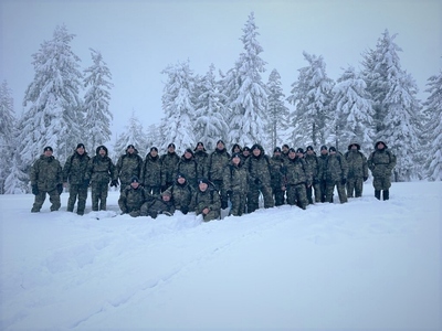 Zimowa sceneria, bardzo dużo śniegu. Grupa umundurowanych funkcjonariuszy Straży Granicznej stoi w półkolu, po dotarciu na miejsce docelowa na Halę Mędralową.