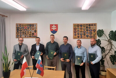 Spotkanie pomocników pełnomocników granicznych pomocnicy pełnomocników granicznych Polski i Słowacji pozujący do wspólnego zdjęcia z podpisanymi dokumentami , które trzymane są w rękach.