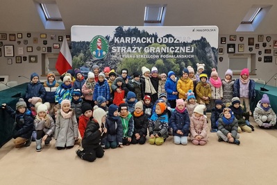 Sala Tradycji w Karpackim Oddziale Straży Granicznej. Na tle baneru z napisem Karpacki Oddział Straży Granicznej stoi grupa około 40 dzieci.