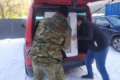 Funkcjonariusz SG wraz z pracownikiem sklepu ładuje do bagażnika samochodu zakupioną w ramach akcji szlachetna paczka kuchenkę gazową.