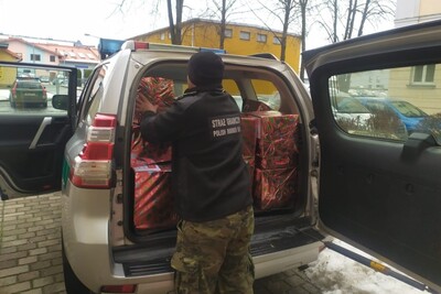 Funkcjonariusz SG pakuje do samochodu służbowego SG  zniesione z Sali tradycji prezenty.