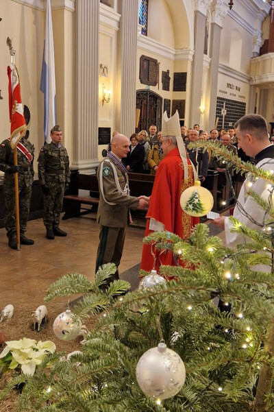Komendant KaOSG wyróżniony przez Biskupa Polowego Komendant Karpackiego Oddziału Straży Granicznej przyjmuje gratulacje  z rąk Biskupa Polowego, który odznaczył Komendanta. uroczystość odbywa się w kościele.