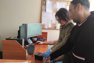 Trzech obywateli Uzbekistanu nielegalnie zatrudnionych w Polsce zatrzymany obywatel Uzbekistanu podczas pobierania jego odcisków palców przez funkcjonariuszkę straży granicznej. wszystko odbywa się w pomieszczeniu służbowym.