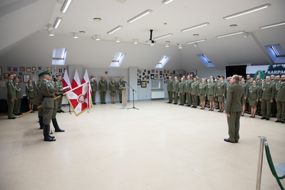 Sala Tradycji karpackiego Oddziału SG. Poczet sztandarowy oraz uczestnicy uroczystości stoją w pozycji na baczność. Major Michalak żegna się ze sztandarem kaosg