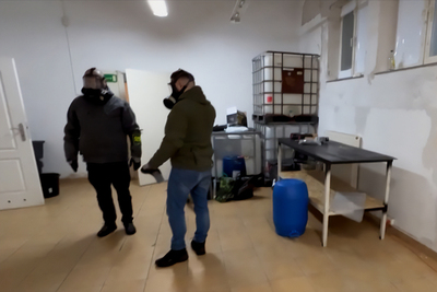 funkcjonariusz straży granicznej i cbśp w maskach gazowych stoją w laboratorium gdzie produkowane były narkotyki