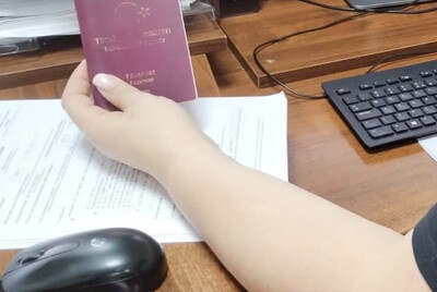na biurku leży klawiatura komputerowa. funkcjonariusz w ręce trzyma paszport jednego z zatrzymanych turków