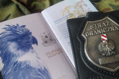 Na materiale w kolorze moro leży paszport filipiński. obok odznaka funkcjonariusza straży granicznej