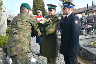 komendant placówki straży granicznej w Zakopanem przekazujący wiązankę kwiatów żołnierzowi podczas uroczystości. asystują mu komendnci straży pożarnej oraz policji w Zakopanem.
