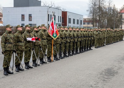 Plac apelowy w komendzie karpackiego oddziału straży granicznej. Poczet flagowy oraz poczet sztandarowy i funkcjonariusze KaOSG uczestniczący w apelu stoją na baczność.