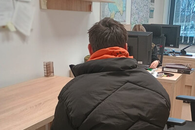 przy biurku siedzi tyłem zatrzymany obywatel Mołdawii. Przed nim funkcjonariuszka siedzi przy drugim biurku i wypełnia dokumentację