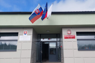Wejście do odnowionego budynku centrum współpracy policyjnej i celnej w trstenie. nad nim wiszą flagi republiki słowacji, unii europejskiej i polska.