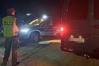 Nepalczyk, Filipińczycy oraz dwoje obywateli Mołdawii zatrzymanych przez tarnowskich funkcjonariuszy SG funkcjonariusz straży granicznej stojący obok zatrzymanego pojazdu. obok niego stoją pojazdy służbowe straży granicznej. zatrzymanie odbywa się nocą.