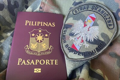 Na materiale w kolorze moro leży paszport obywatela Filipin i plakietka SG