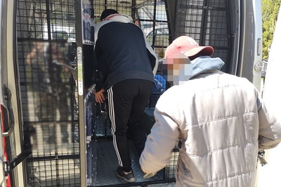 Zatrzymani cudzoziemcy wchodzą do więźniarki SG tylnym wejściem.
