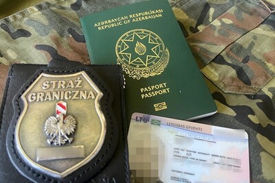 Na materiale w kolorze moro leży paszport zatrzymanego Azera, litewska karta pobytu oraz odznaka funkcjonariusza sg