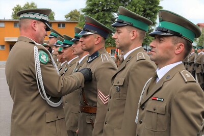 Komendant Karpackiego Oddziału Straży Granicznej wręcza odznaczenia funkcjonariuszom  karpackiego oddziału straży granicznej. W tle stoją pododdziały zebrane na uroczystości.