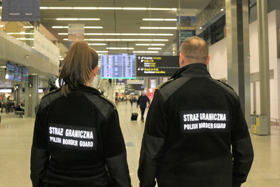 Dwóch funkcjonariuszy Straży Granicznej pełniący służbę w porcie lotniczym w hali odlotów.
