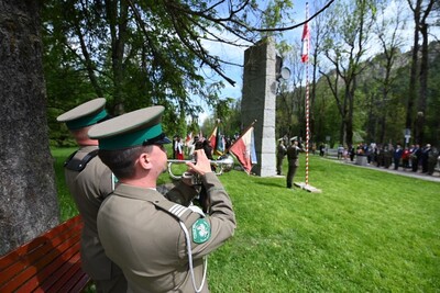 funkcjonariusz straży granicznej grający na trąbce, zwany sygnalistą. w tle widoczny jest Pomnik oraz zebrani na uroczystości ludzie.