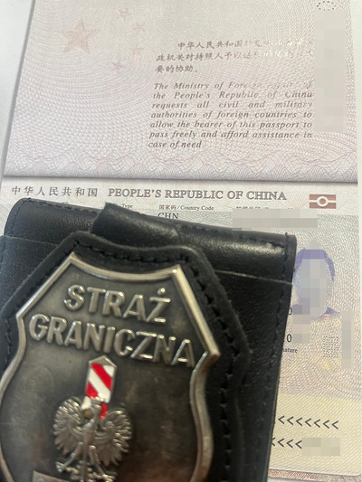 Zdjęcie przedstawia odznakę straży granicznej na tle chińskiego paszportu
