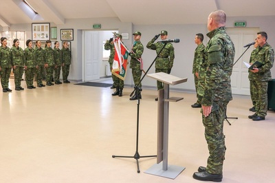 komendant karpackiego oddziału straży granicznej stoi na baczność podczas odgrywania hasła wojska polskiego. w tle widoczny jest sztandar oddziału.