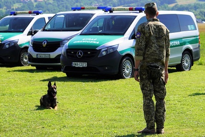 ukraiński żołnierz ćwiczy ze swoim psem służbowym. w tle pojazdy służbowe straży granicznej.