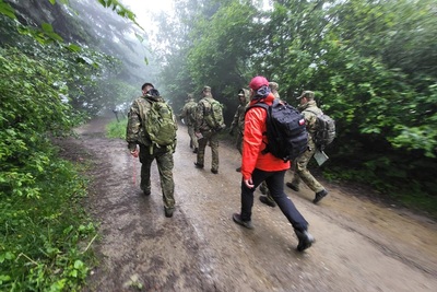 funkcjonariusze straży granicznej idą błotnista leśną drogą podczas szkolenia w terenie.