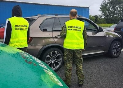 na autostradzie jest wstrzymany ruch. miedzy samochodami stoi dwóch funkcjonariuszy straży granicznej w  odblaskowych kamizelkach.