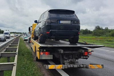 na jednym z pasów autostrady stoi laweta, na niej samochód osobowy typu suv